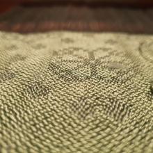 Close up of dark abd light green damask cloth with a circle made of dots and a rise motif with the circle