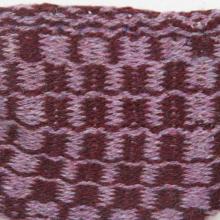 A weft faced woven small bag with a checkered pattern in light and dark purple.