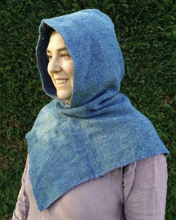 A woman wearing a blue hood woven with a grey warp and blue weft with a v neckline.