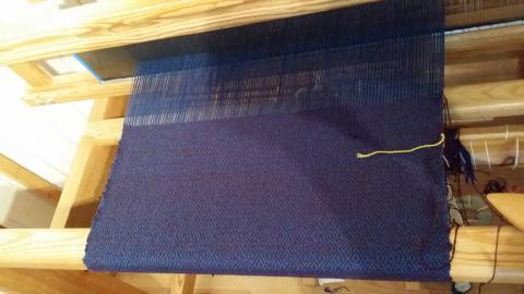 A Blue warp on the loom being woven with a purple weft