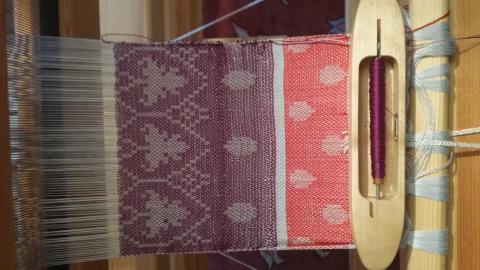 A grey cotton warp with a tree and dots motif, motif is in grey and backgrounds are purple then red.