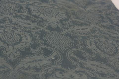 A dark and light creen cloth woven in damask with large overall floral designs.